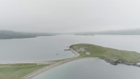 slow wide drone shot of a small island connected to the mainland with a single house on it outside durness on the north coast of scotland