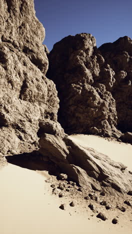 a desolate desert canyon with towering rock formations and a clear blue sky