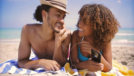 Couple-on-beach-listening-to-music-and-smiling