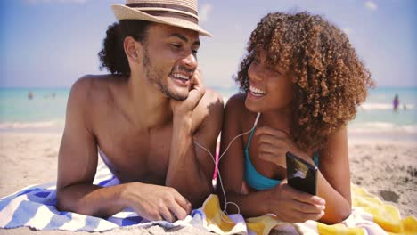 couple on beach listening to music and smiling