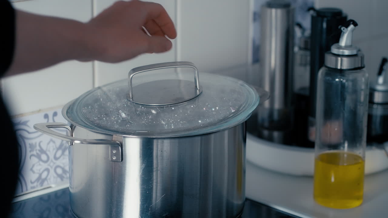 el agua hierve en una olla grande de hierro en la estufa mientras la mujer abre la tapa para liberar vapor en cámara lenta