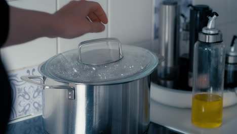 el agua hierve en una olla grande de hierro en la estufa mientras la mujer abre la tapa para liberar vapor en cámara lenta