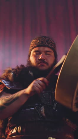 plump man in traditional altai clothes plays shamanic drum at fertility ritual in ail. performance with magical elements. siberian spiritualism