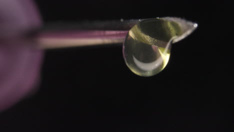 close-up of syringe tip with a few drops of liquid dripping