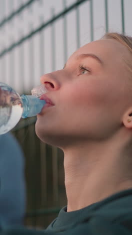 ladies relaxing outdoors after exercise, seated and drinking water from bottles to stay hydrated, enjoying a well-deserved break after an intense workout session