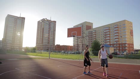 two men playing basketball on an outdoor court