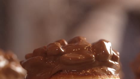 caramel donut being decorated gold spray close up