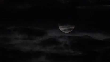beautiful full moon crossing the sky, clouds passing in front