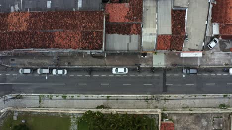 Top-bird's-eye-shot-of-a-small-Brazilian-street-with-cars-and-motorcycles-parked-and-driving-by-in-the-historic-downtown-of-the-coastal-capital-city-of-Joao-Pessoa,-Paraiba,-Brazil-during-golden-hour