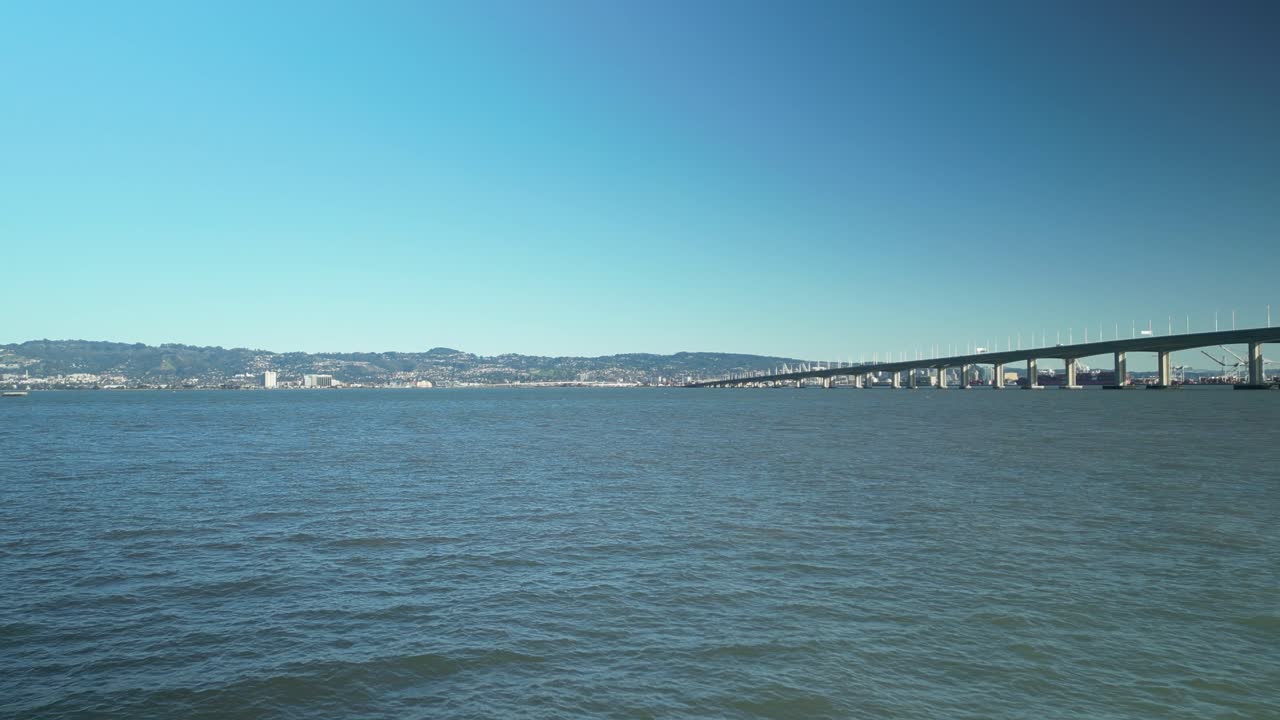 Push in drone shot of San Francisco-Oakland Bay Bridge with Pacific Ocean and blue sky in California, USA