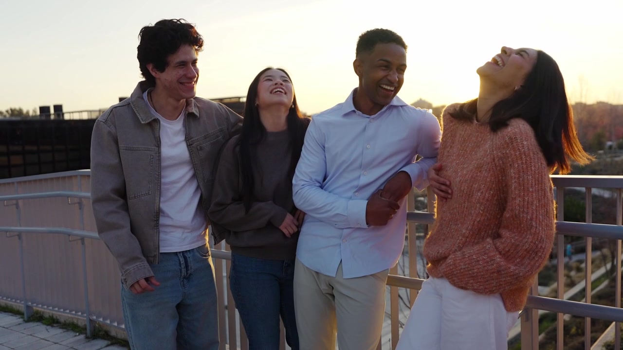 Amigos multiétnicos riendo y conversando al aire libre al atardecer.