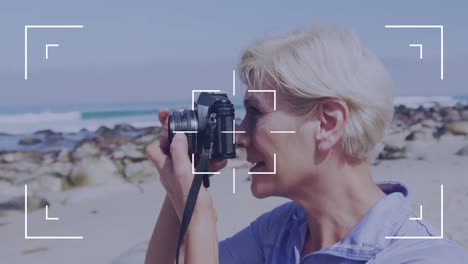 happy caucasian senior woman taking pictures by the coast over icons of digital camera