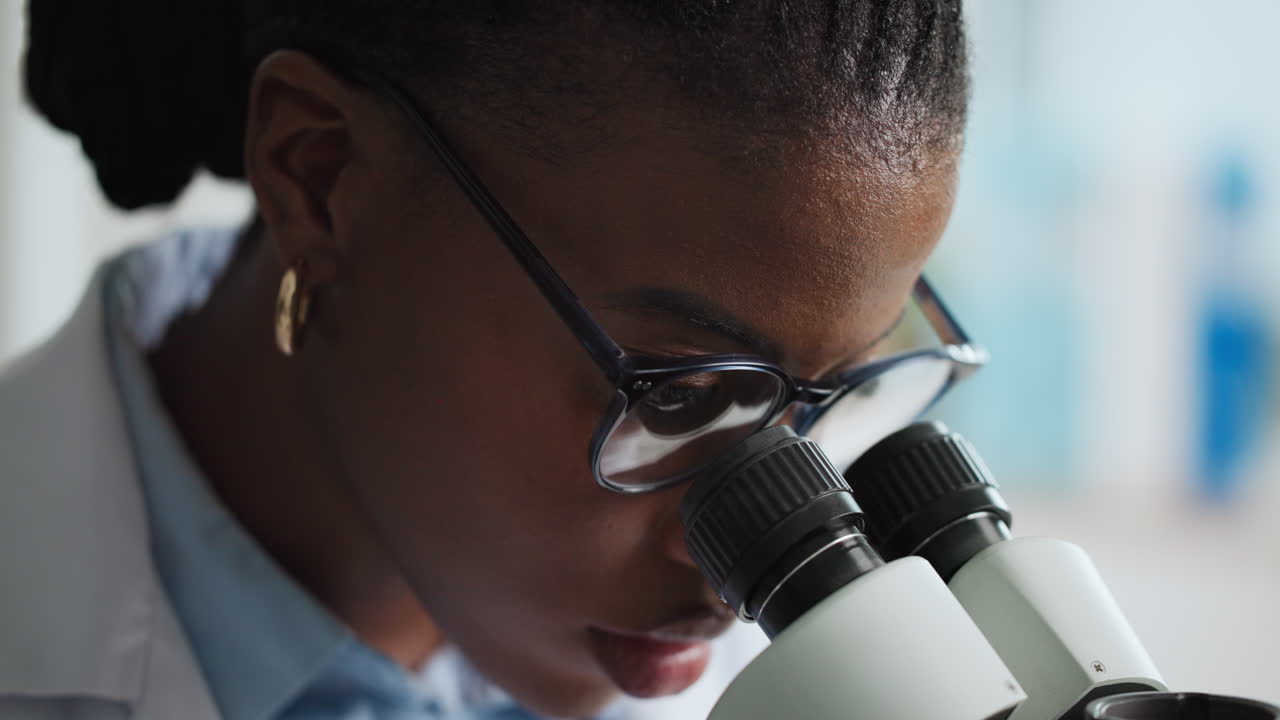 Scienziato afroamericano che lavora con il microscopio