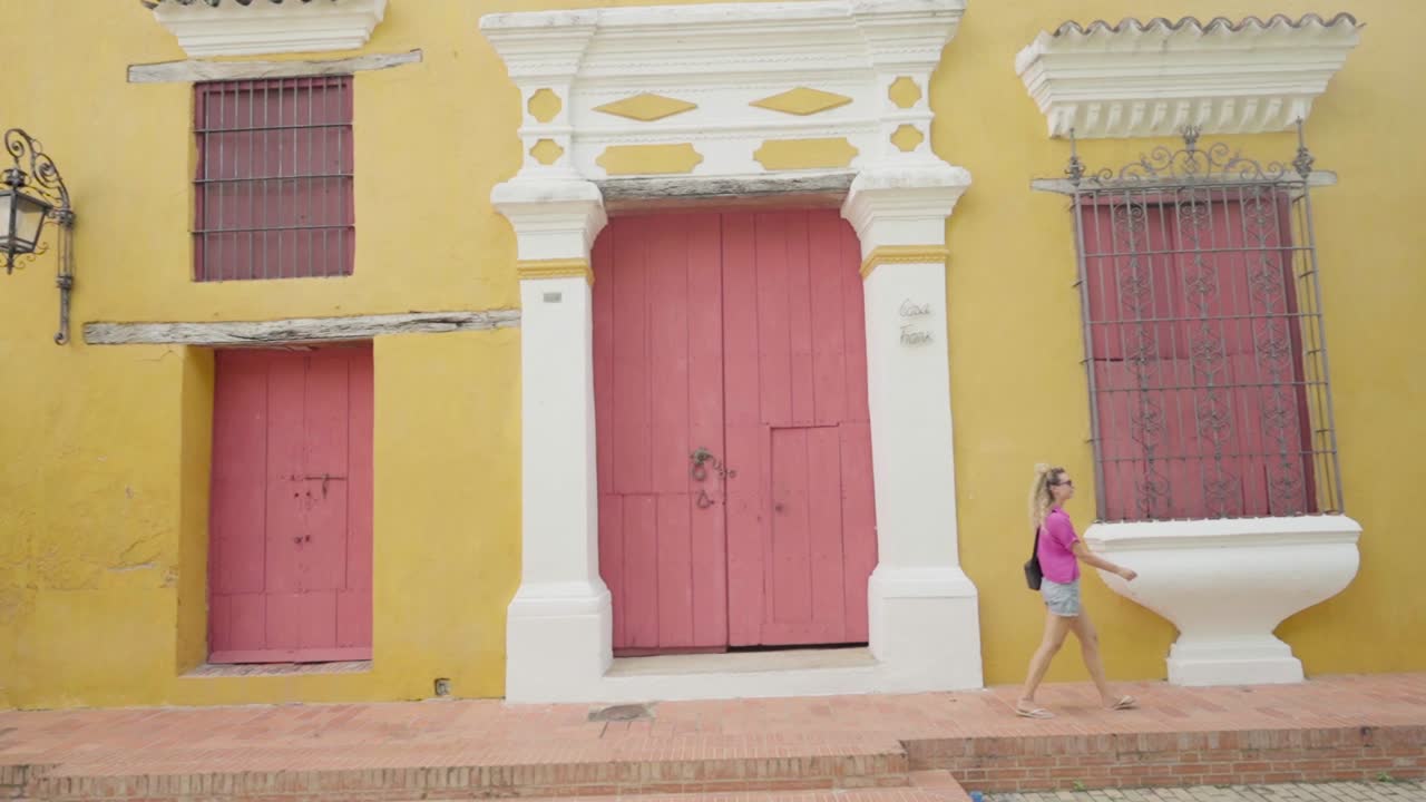 Female tourist walking along a colorful street with colonial architecture in mompox, colombia