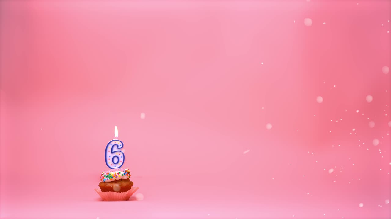 cupcake de celebración de cumpleaños feliz con glaseado, chispas y una llama de vela encendida de 6 años ardiendo y moviéndose sobre un fondo de coral rosa - bucle de boomerang sin fisuras