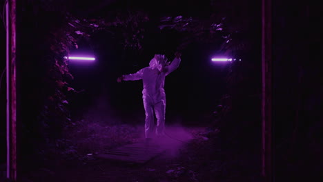 person in a suit dancing in a purple lit forest at night