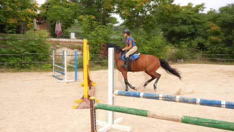 Rider guiding her horse toward a hurdle during competition training. Slow motion