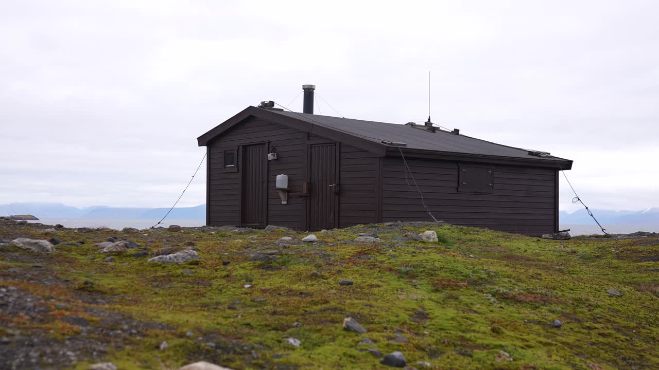 cabaña de madera en la cima de una colina en el paisaje de una isla en el archipiélago de svalbard, noruega