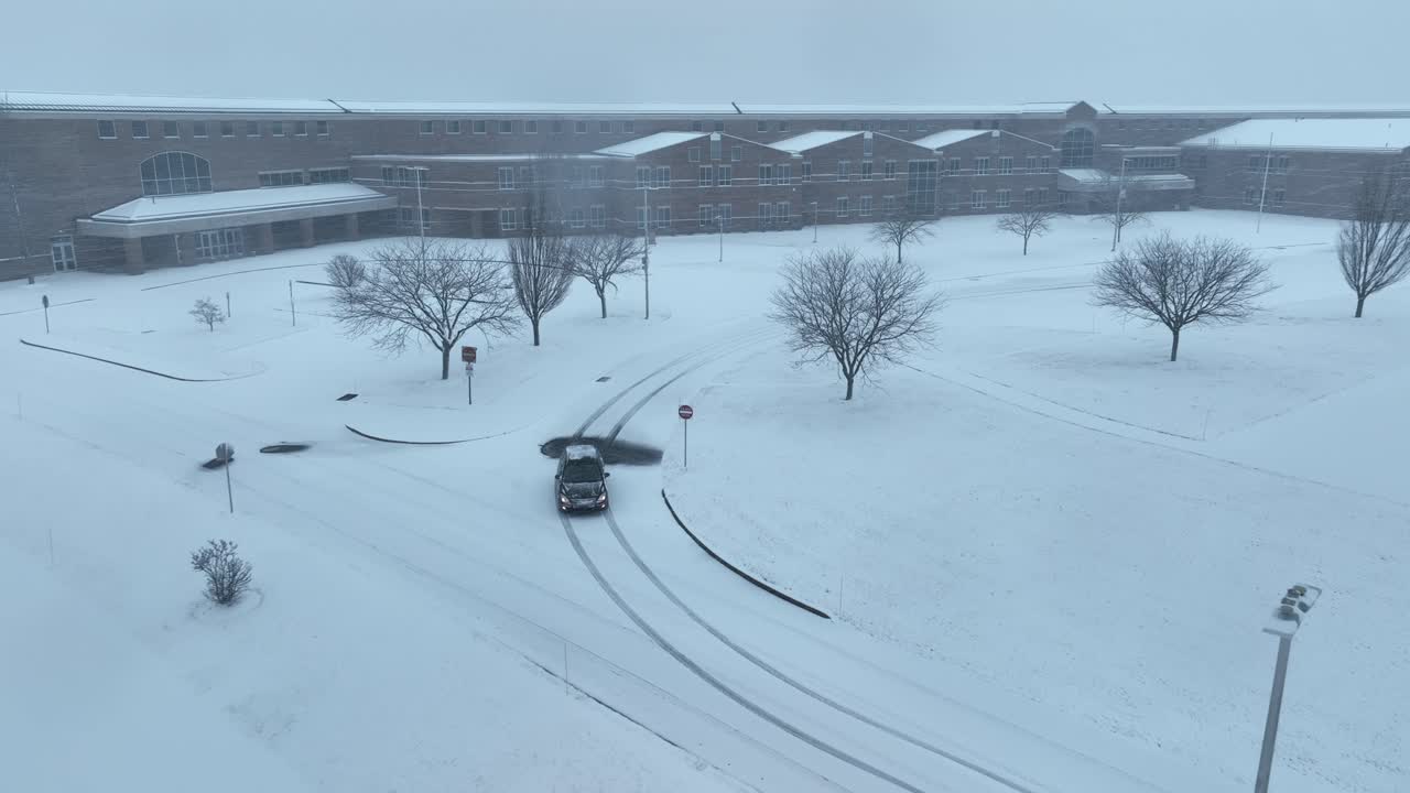 Snowy Winter Day at a Large Building with Bare Trees and Vehicle Tracks