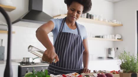 happy african american woman preparing dinner in kitchen