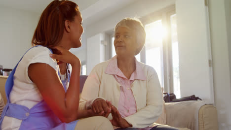 female doctor comforting senior woman in living room 4k