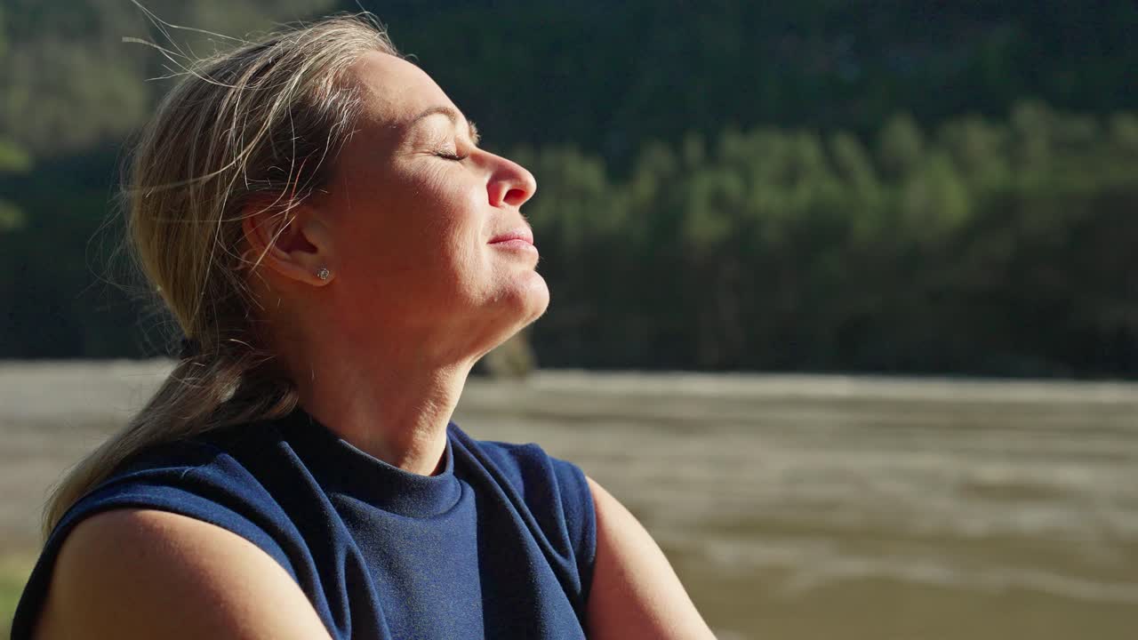 una mujer relajándose junto a un río.