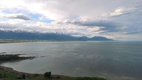 kaikoura coastline, calm sea and snow-capped mountain range in south island of new zealand. - aerial shot