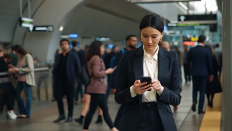 businesswoman using smartphone at a train station