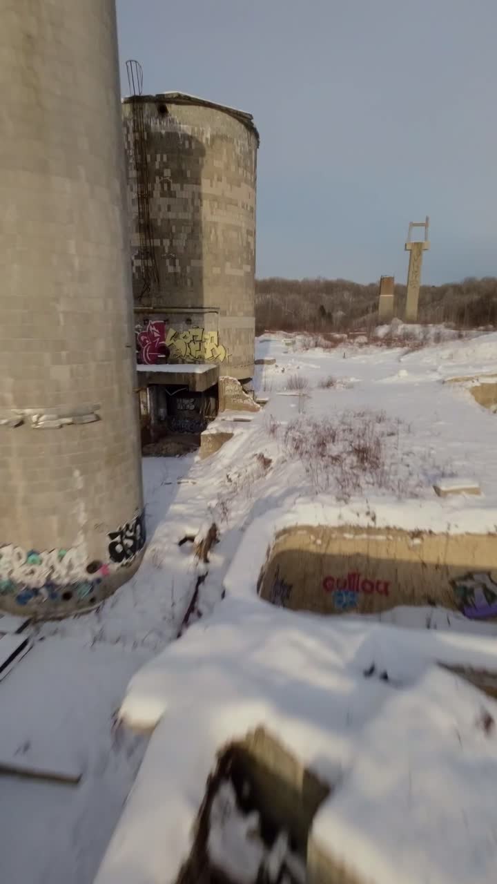 Drone FPV della Belgo Factory, Shawinigan, Quebec, Canada, che sorvola vicino a silos abbandonati in cemento con terreno innevato, sito industriale storico durante l'inverno
