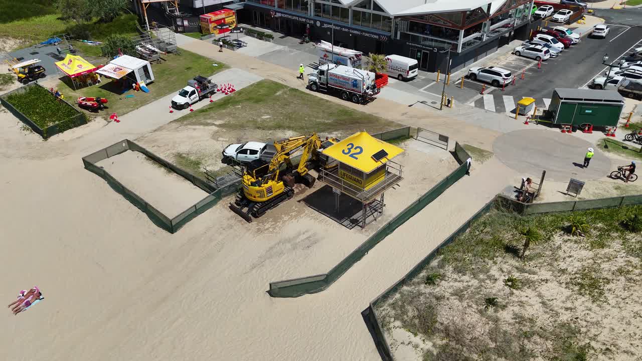 Aerial view of construction site on Gold Coast beach with machinery and life-saving tower under clear skies