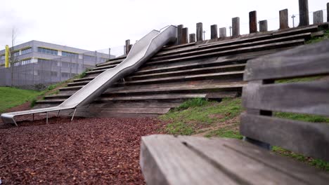 Empty-children-playground-closed-during-the-Covid-19-Coronavirus-pandemic-lockdown-in-the-UK,-deserted-metallic-slide-and-wooden-benches