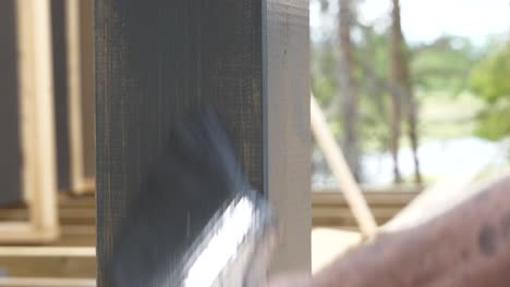 male hand painting a house in dark grey prime color