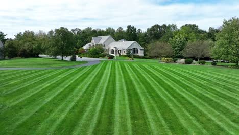 striped lawn leading to a large suburban home with trees