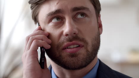 Young-businessman-talking-phone-at-remote-office.-Close-up-guy-calling-phone.