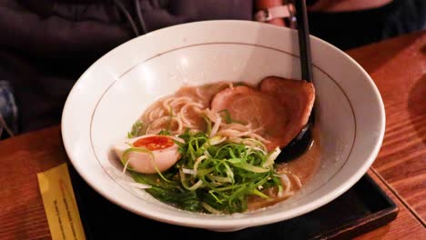 chopsticks lifting noodles from a ramen bowl