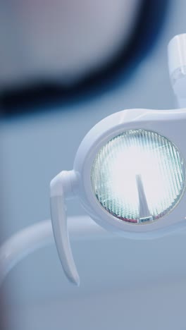 modern dentist lamp glows in vertical frame at bright clinic with white interior