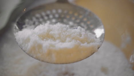 Slow-motion-macro-up-close-metal-strainer-sifting-bright-red-cranberries-and-sugar-in-clear-glass-bowl