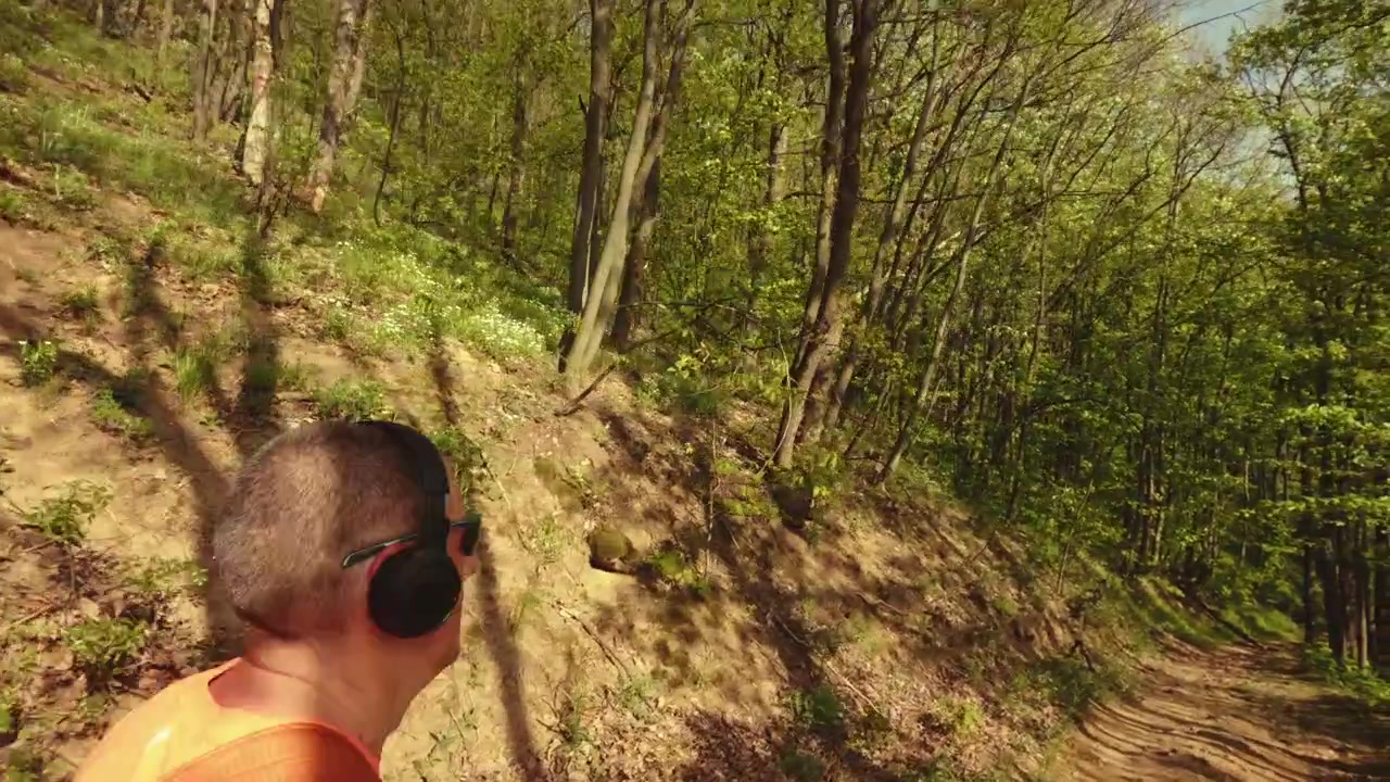 Hochwertiges 4K B-Roll-Material eines aktiven Mannes mittleren Alters (50+) mit Rucksack und Kopfhörern beim Laufen, Wandern und Gehen auf einem Waldweg. Konzept von gesundem Altern, aktivem Lebensstil.