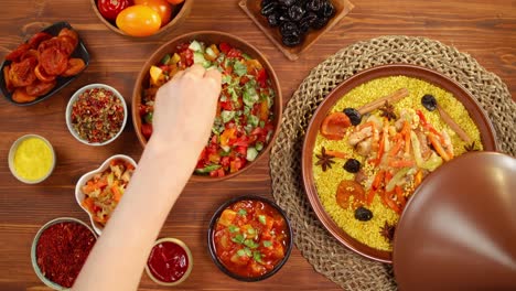 moroccan cuisine top view. tajine, traditional dish made of lamb and eggplant, putting parsley into vegetable salad. middle eastern culture. couscous with mutton, delicious rice. homemade food