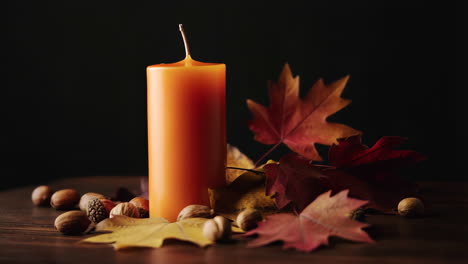 autumn candle with fall leaves and nuts