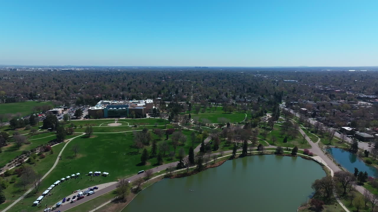 City Park Denver Museum and natural Science building Colorado Lake Pavilion vibrant spring summer aerial drone front range cityscape green lush grass trees blossom sunny blue sky forward motion