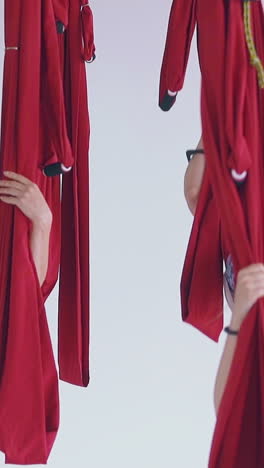 happy women group enjoys swinging and sitting in red hammocks relaxing after fly yoga workout slow motion