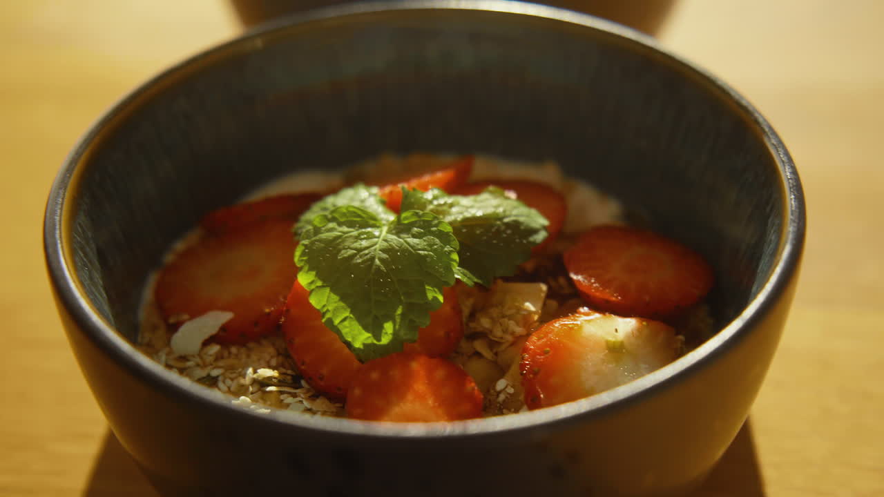 nær yoghurt med hjemmelavet granola og jordbær dekoreret med mynte i en smuk skål