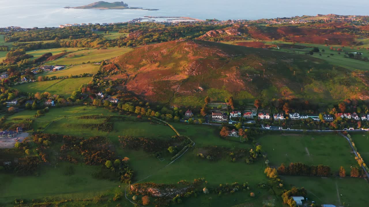 Drone Orbit Over Howth with Dublin Bus Passing Along Distant Road Beneath Sunset Light