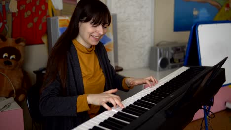 a young woman plays an electronic synthesizer, her hands touch the keys.