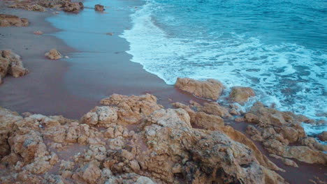 The-untamed-shoreline-of-Portugal-features-rocky-formations-splashed-by-the-serene-ocean-waves,-illuminated-by-the-radiant-glow-of-a-delightful-day