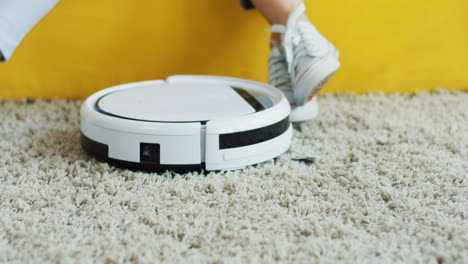 close up of the mini vacuum cleaner on the floor and female and kids feet on the background