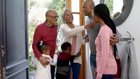 happy african american parents, son and daughter welcoming visiting grandparents, slow motion