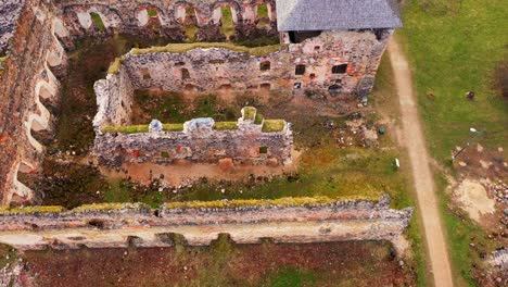 Exterior-De-Las-Antiguas-Ruinas-Del-Castillo-En-El-Exterior-Verde,-Drone-Aéreo-Disparado-De-Arriba-Hacia-Abajo