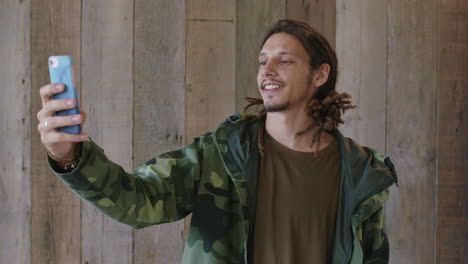 portrait of young mixed race man dreadlocks hairstyle posing taking selfie photo smiling confident using smartphone mobile technology